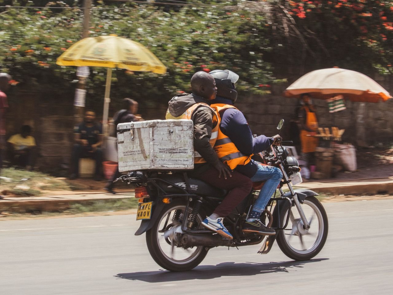 Motorcyclist and passenger delivering goods in Nairobi, Kenya's busy streets.