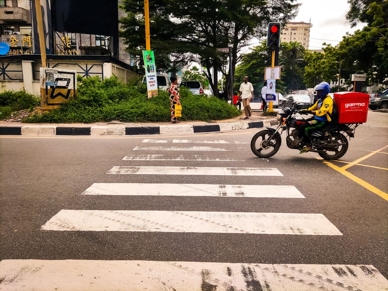 Dynamic street view featuring a delivery motorbike and pedestrians in Lagos, Nigeria.